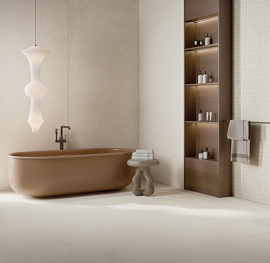 Editorial bathroom with warm parchment travertine-effect porcelain stoneware floor and walls, terracotta freestanding tub and walnut storage niche